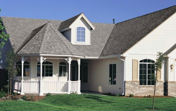 White house with round porch and shingled roof.